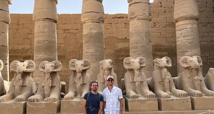 Zwei Touristen stehen vor Widder-Statuen.