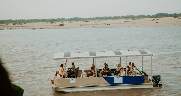 Groep mensen op een boot die langs een rivier vaart.