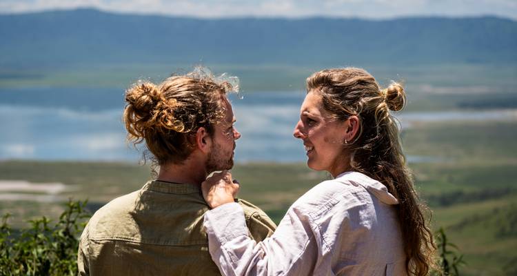 Pareja mirándose el uno al otro con un lago y montañas de fondo.