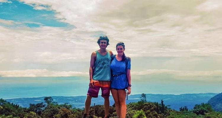 Ein Paar, das auf einem Berg mit einer weiten Landschaft im Hintergrund posiert.