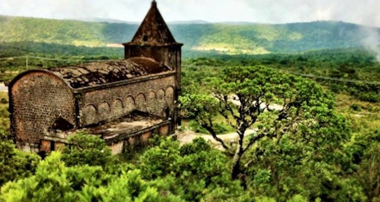 Eine alte Kirche in einer grünen Landschaft.