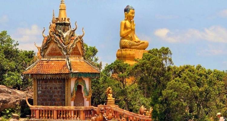 Een tempel en een gouden Boeddhabeeld tegen een heldere hemel.