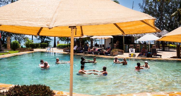 People enjoying a swimming pool under sun umbrellas.