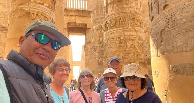 Una selfie casi duplicada con viajeros mayores entre las columnas decoradas del Templo de Karnak.