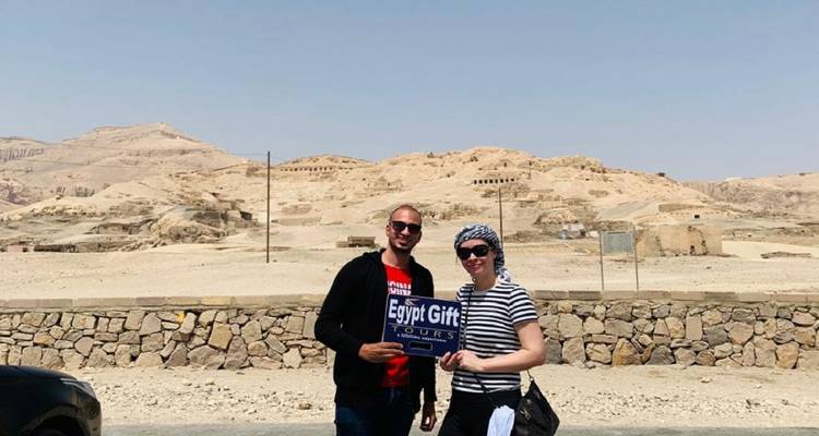 Toeristen met een bord in een kaal landschap op de achtergrond.