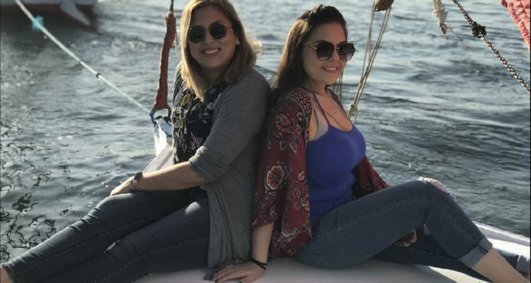 Zwei Frauen sitzen auf einem Boot über dem Wasser.