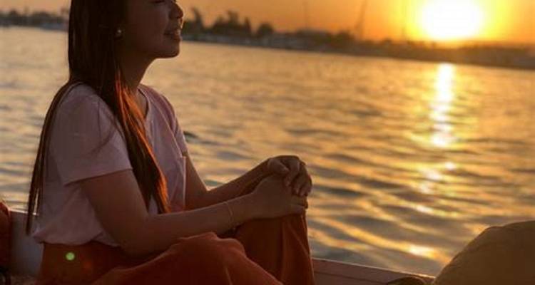 Femme assise sur un bateau profitant du coucher de soleil sur le Nil.