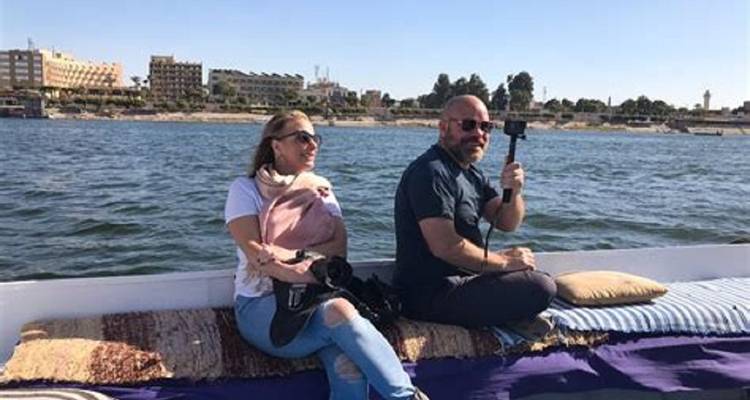 Deux personnes assises sur un bateau avec des appareils photo et une perche à selfie.