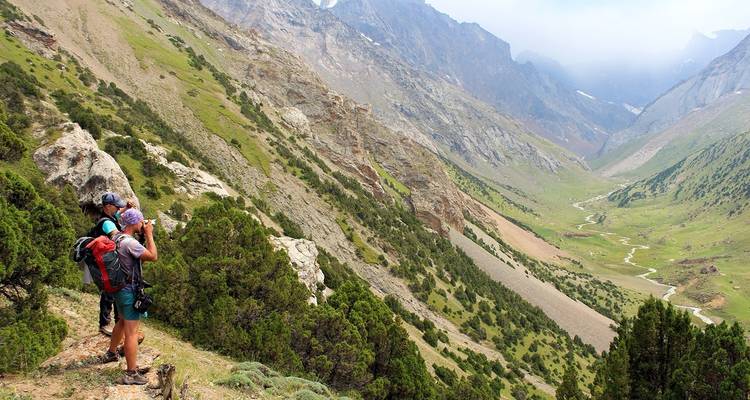 Des randonneurs prenant des photos d'une vaste vallée de montagne.