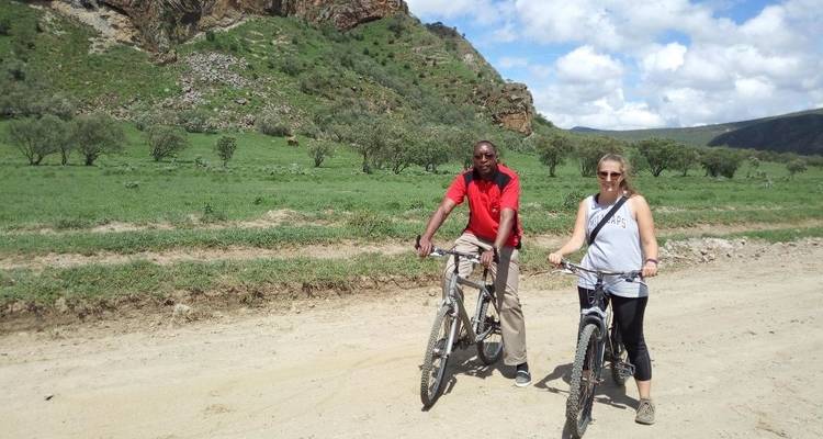 Zwei Personen posieren mit Fahrrädern auf einer unbefestigten Straße.