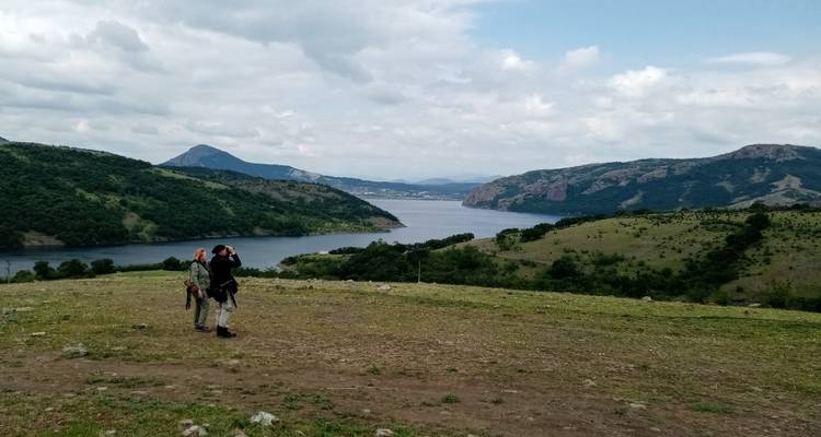 Des gens avec des jumelles admirant un lac pittoresque et des collines.
