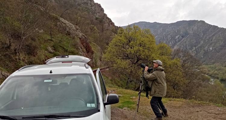 Personne avec un appareil photo sur une colline au terrain rocheux.