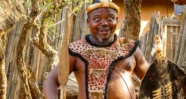 Person in traditioneller Kleidung, die in einer Dorfumgebung lächelt.