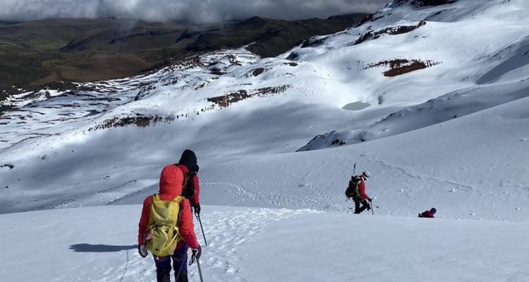 Les alpinistes en vestes colorées traversent à pied un vaste versant enneigé haut dans les Andes.