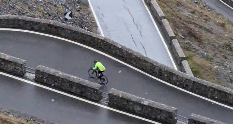 Cycliste négociant un virage serré sur une route de montagne.