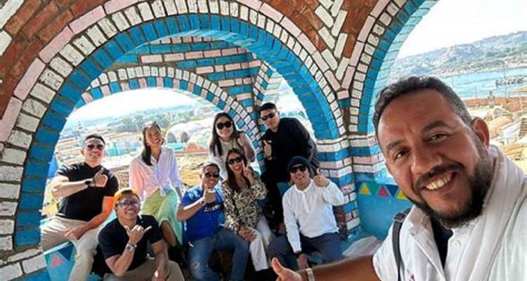 Reisende lächeln unter farbenfrohen Ziegelbögen eines nubischen Hauses mit Blick auf den Nil.