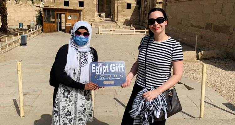 Deux femmes posant devant un temple en tenant une banderole.