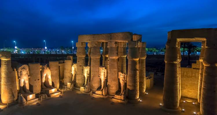 Luxor Tempel verlicht in de avond met een bewolkte hemel erboven.