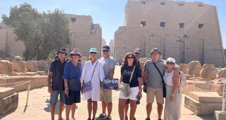 Groepsfoto binnen de Karnak Tempel met Egypt Gift Tours bord, stenen beelden op de achtergrond.