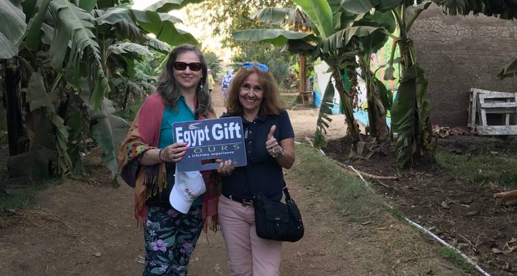 Deux femmes tenant une pancarte près de plants de bananiers.