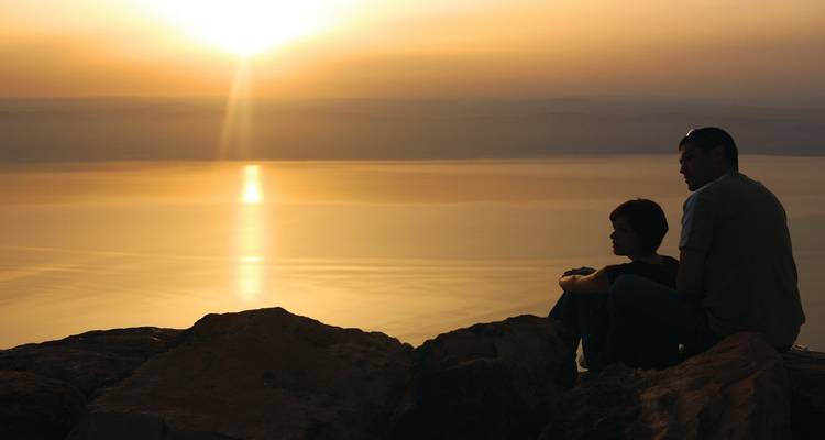 Couple en silhouette regardant un coucher de soleil sur l'eau.