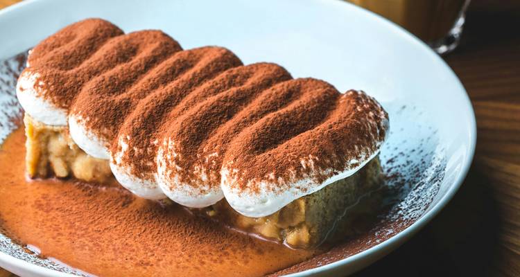 Assiette de dessert de style tiramisu en couches, généreusement saupoudrée de poudre de cacao.