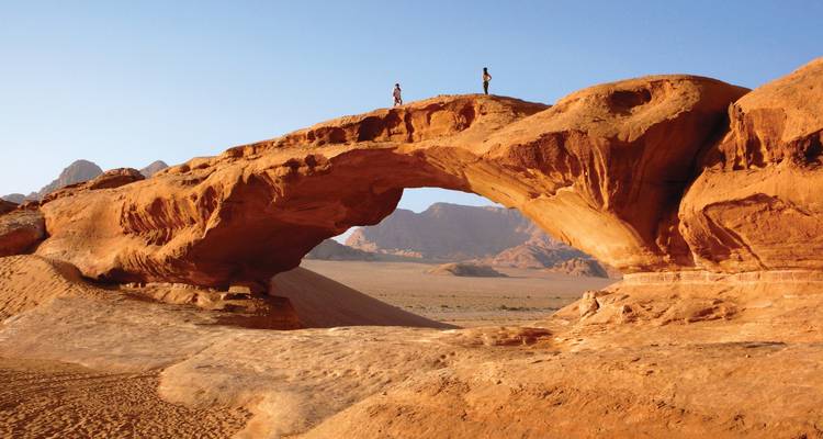 Natural rock arch with people standing on it.