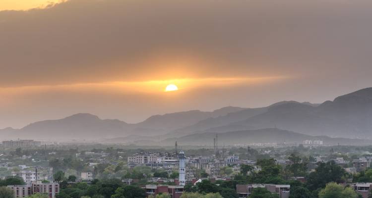 Coucher de soleil sur une ville avec des montagnes en arrière-plan.