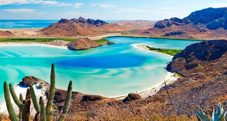 Levendige lagune omgeven door woestijnlandschap en blauwe wateren.
