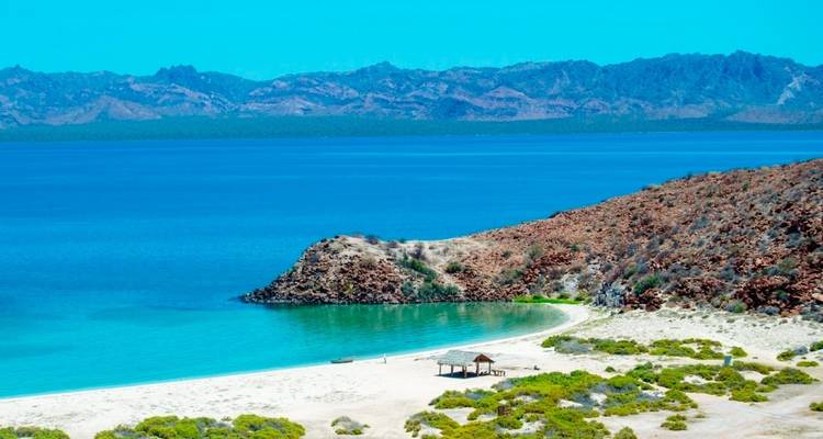 Afgelegen strand met turquoise water en kustelijke heuvels.