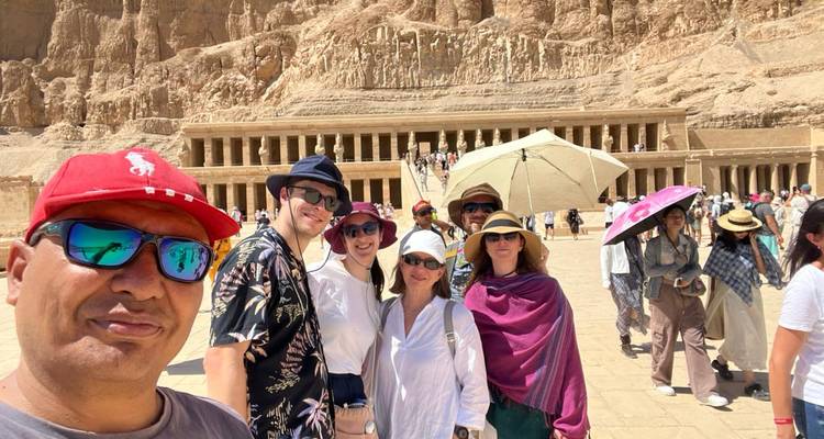 Des touristes prennent un selfie devant le temple d'Hatchepsout taillé dans une falaise.