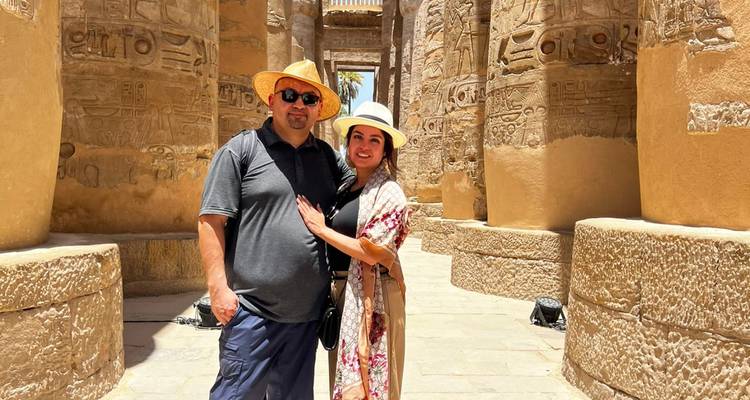 Couple posant parmi d'immenses colonnes couvertes de hiéroglyphes à l'intérieur du temple de Karnak.