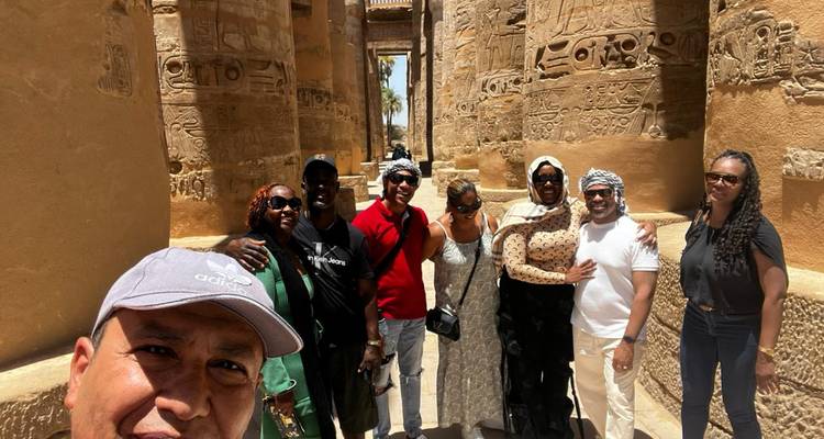 Grand selfie de groupe à l'intérieur d'une salle de temple richement sculptée d'hiéroglyphes.