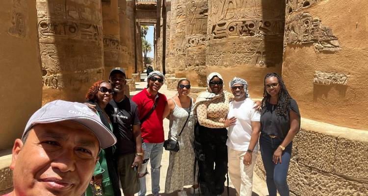 Groupe de voyageurs souriants parmi des colonnes géantes de grès aux sculptures complexes.