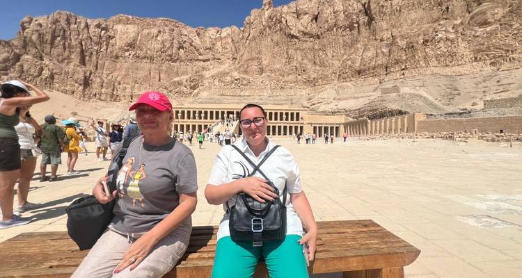 Deux femmes sont assises sur un banc dans la vaste cour devant le temple d'Hatchepsout.
