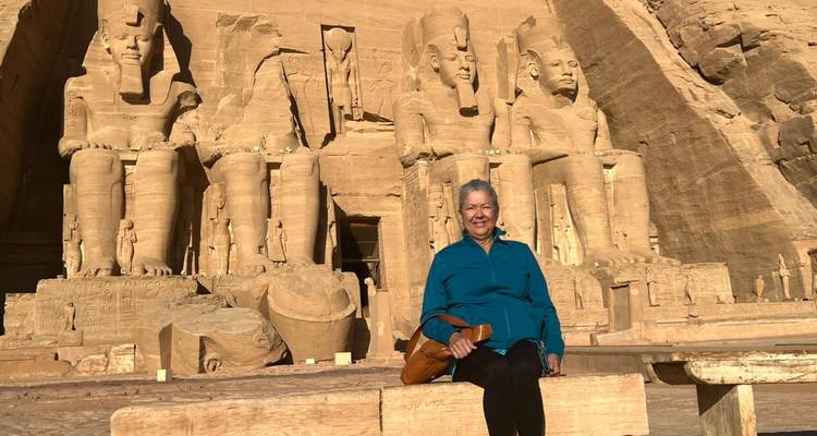Vrouw zit op een bankje voor de indrukwekkende standbeelden van Abu Simbel