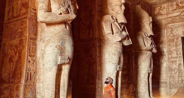 Bezoeker die omhoog kijkt naar imposante binnenstatuen in het schemerig verlichte heiligdom van Abu Simbel.