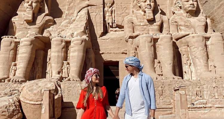 Stel dat patroonsjaal draagt en hand in hand vast voor de indrukwekkende gevel van Abu Simbel.