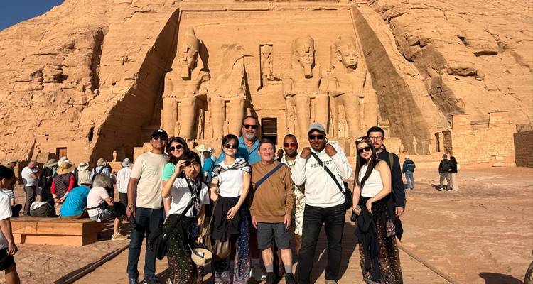 Toeristengroep die samen poseren op de weg naar Abu Simbel met towering statues op de achtergrond.