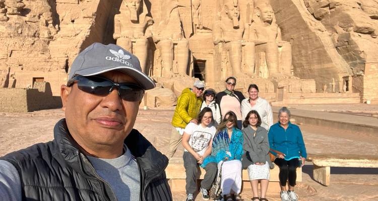 Selfie van een man met een grotere groep die voor de massieve gevel van Abu Simbel zit.