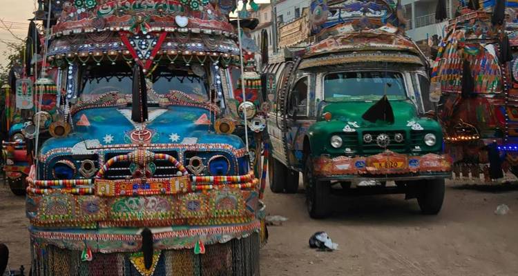 Geschmückte Lastwagen, die an einer Straße geparkt sind und lebendige kulturelle Kunstwerke zeigen.