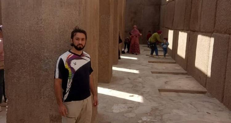 Homme debout parmi d'anciennes colonnes de pierre.