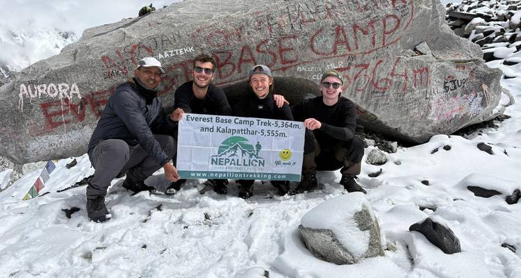 Des randonneurs posant au camp de base de l'Everest avec un panneau.