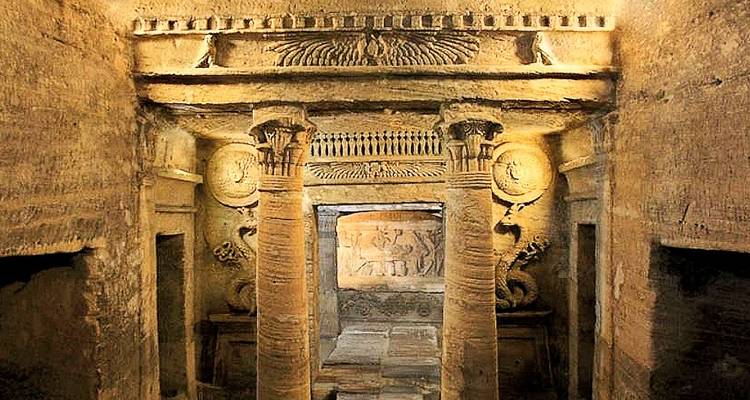 Tombes anciennes et colonnes dans un site souterrain historique.