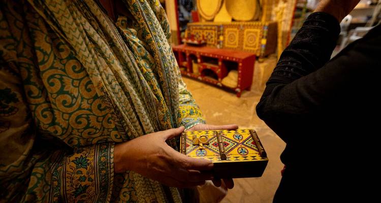 Gros plan d'une boîte aux motifs colorés tenue par une personne en vêtements traditionnels.