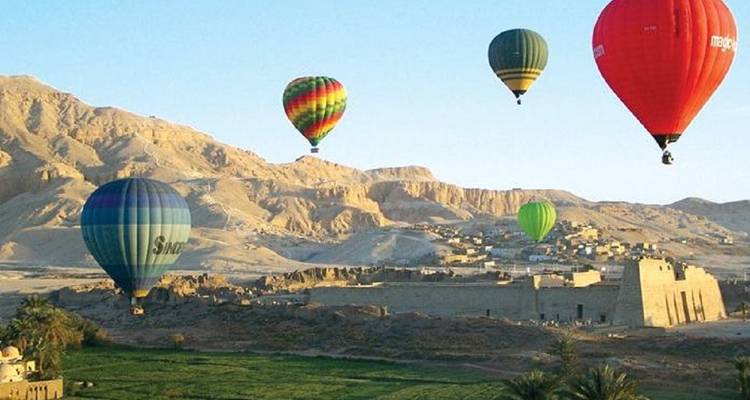 Mehrere Heißluftballons über einer Wüstenlandschaft.