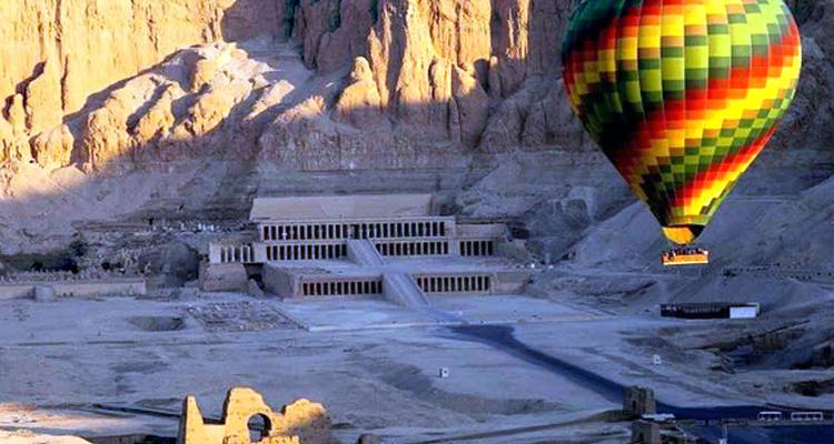 Heißluftballon fliegt über antike ägyptische Ruinen.