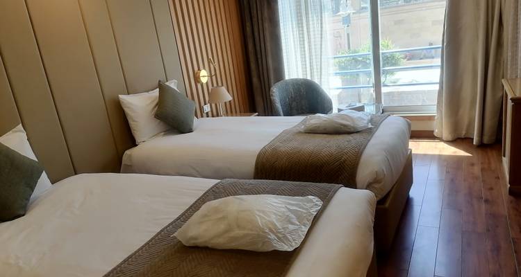 Innenraum eines Hotelzimmers mit zwei Einzelbetten und einem Balkon.