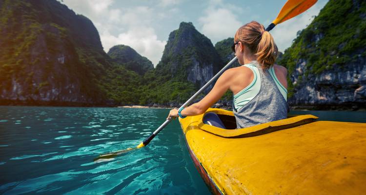 Persoon die kajakvart op een meer omringd door hoge kalksteenrotsen.