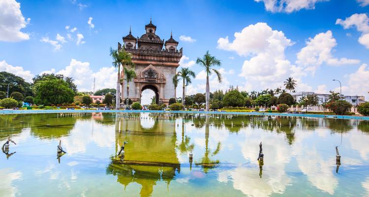 Historisch monument weerspiegeld in water met palmbomen eromheen.